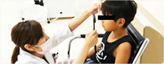 眼科醫生為男童進行斜視矯正訓練